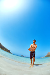 Wall Mural - man standing in the sea on the beach. Smiling man looking at camera and He raises both hands up as if playing the ball