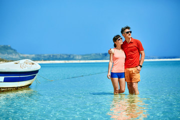 Wall Mural - couple standing in the sea near the boat. They hold each other's hands