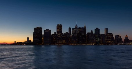 Fototapete - Time lapse cityscape view of the New York City Financial District and East River with passing boats. Lower Manhattan skyscrapers between sunset and dusk with city lights