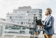 © Westend61 - Businessman standing on bridge using laptop