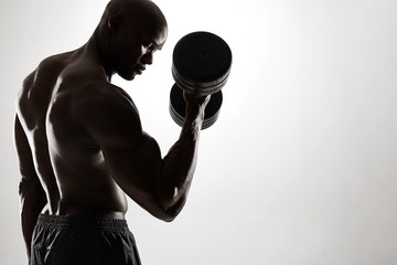 Young african man exercising with heavy dumbbells