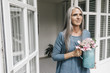 © Westend61 - Portrait of smiling woman with pitcher of Hydrangea in front of her house