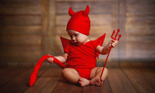 Funny Baby In Devil Halloween Costume On Wooden Background