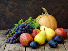 Still Life Of Autumn Fruits: Pumpkin, Grape, Apple, Pear, Plum On A Wooden Background. Selective Focus