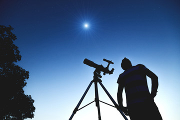 Wall Mural - man looking at the stars with telescope beside him.