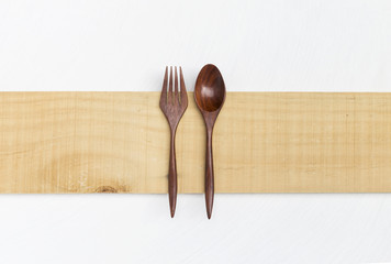 Red wood fork and spoon on wooden plate