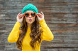 Beautiful brunette woman in sunglasses and knitted  cap blowing
