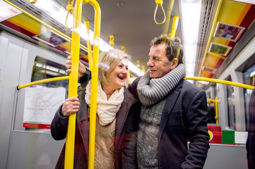 Wall Mural - Senior couple standing in a crowded subway train