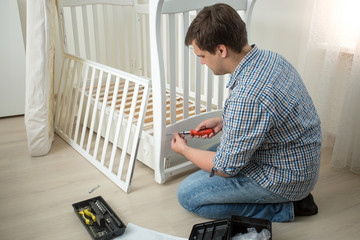 Man assembling baby's cot after moving in new house