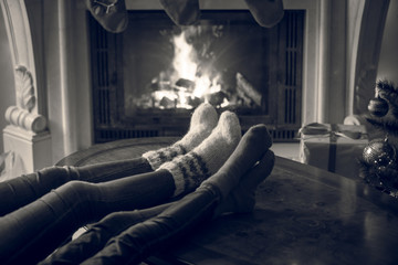 Black and white image of family feet in woolen socks warming at