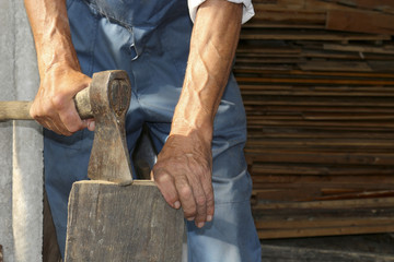 The worker, a man with an ax chopping firewood . Employee.