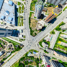 Aerial City View With Crossroads And Roads, Houses, Buildings, Parks And Parking Lots, Bridges. Urban Landscape. Copter Shot. Panoramic Image.