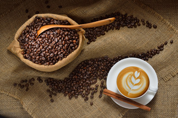 Wall Mural - Top view of cup of coffee latte and coffee beans on burlap background