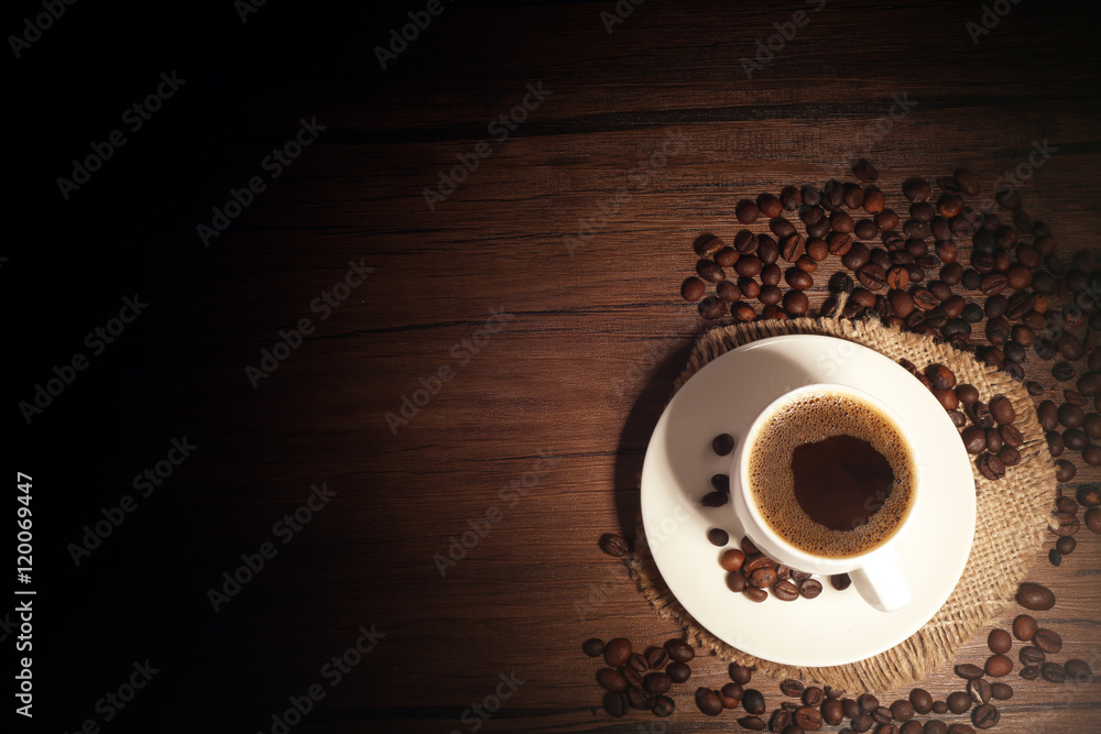 Cup of coffee with beans on wooden background