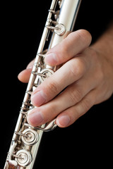 Wall Mural -  Flute in the musician's hands on a black background closeup