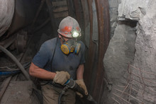 Miner In A Respirator With A Jackhammer In Underground Coal Mine