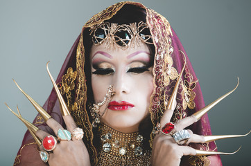 Headshot woman dressed in traditional hindu clothing, heavily decorated in gold and elegant veil, extremely long fingernails, posing artistically for camera, hindusim dancer concept