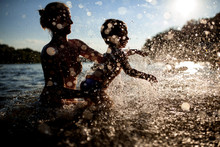 Mother Swim With Baby In Blue Water At Sunset;