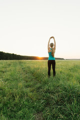 Young female resting after an active fitness training standing outdoor. Satisfied fit woman resting after an active fitness training