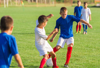 Wall Mural - Boys playing football soccer game on sports field