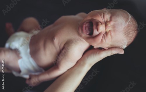 Fotografía Portrait of newborn baby crying in parents' arms. Mother hands.