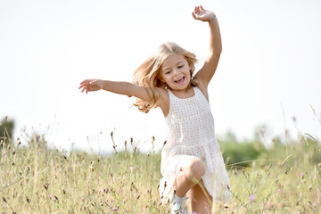 Wall Mural - Little girl running in country field in summer