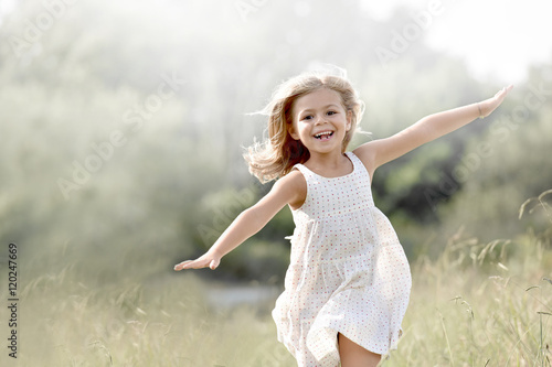 Fototapeta Little girl running in country field in summer