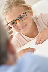 Little girl at the optician trying different eyeglasses