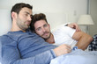 © Picxel Creative - Portrait Of Gay Male Couple At Home Relaxing In Bed Together
