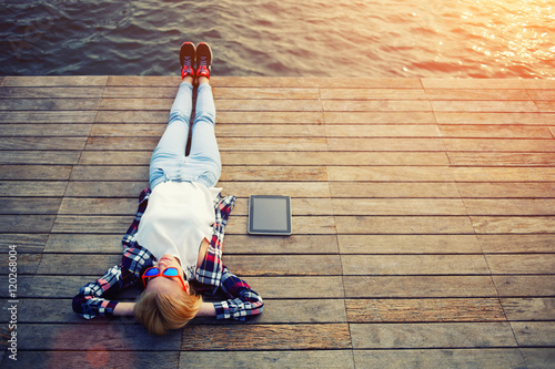 Fotografia Top view young woman lying on a wooden jetty enjoying the sunshine
