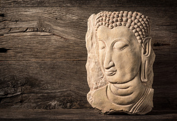 low relief sandstone sculpture of buddha image on old wood