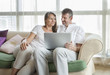 © katiekk2 - happy couple sitting on a sofa and working in the laptop