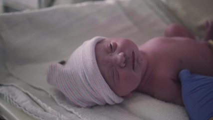 nurse puts stocking hat on newborn newborn baby girl just born in hospital