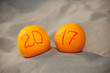 © Dimid - Two ripe oranges lie in the sand on the beach, they were writing the number in honor of 2017. Celebrating the New Year in the ocean or the sea.