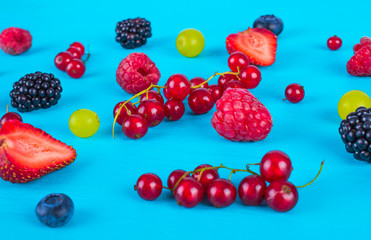 Wall Mural - Various fresh berries and fruits on a blue background.