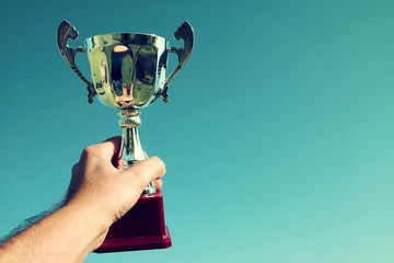 Wall Mural - man holding up a trophy cup as a winner