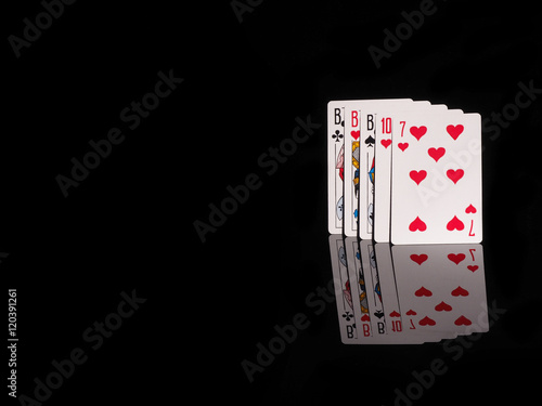фотография Three of a Kind playing cards isolated on black background.