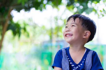 Wall Mural - Happy asian boy looking up at park. Outdoors in the daytime