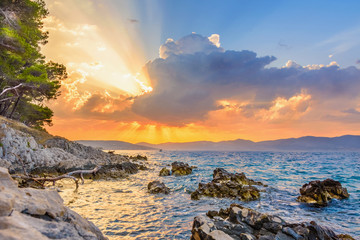 Sun beams or light rays breaking through the clouds at sunset, over the sea