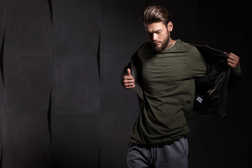 Man with beard in green t-shirt on gray cement background looking down