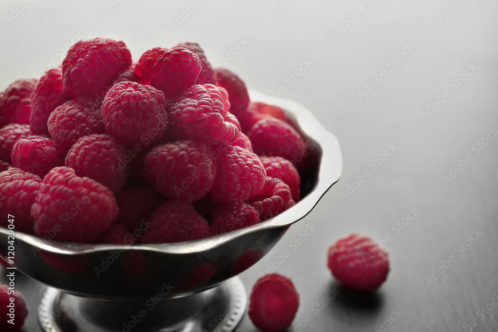 Fresh raspberries in bowl on table, closeup