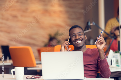 Fényképezés African American businessman on the phone sitting at the computer in his startup