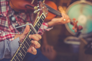 Selective focus hands man playing guitar on walking street, color effect