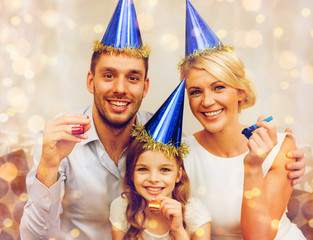 Wall Mural - smiling family in blue hats blowing favor horns