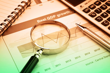 Magnifying glass, pen and calculator on growth financial chart a