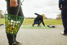 Close-up Of Woman Holding Basket Filled With Golf Balls