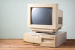 © reshoot - old and obsolete computer on old wood table with concrete wall background