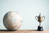 Fototapeta Sport - still life photography : old football and vintage trophy on old wood table in championship concept