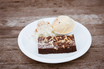 Brownie on white plate with ice cream