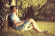 © guas - Relaxing man sitting under a tree with eyes closed meditating an